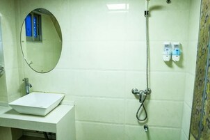 Un baño con un lavabo blanco, un espejo, una ducha y dos dispensadores de jabón.