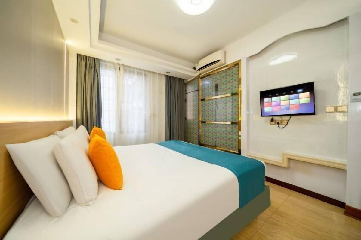 A hotel room with a bed, curtains, a TV, and a wardrobe.