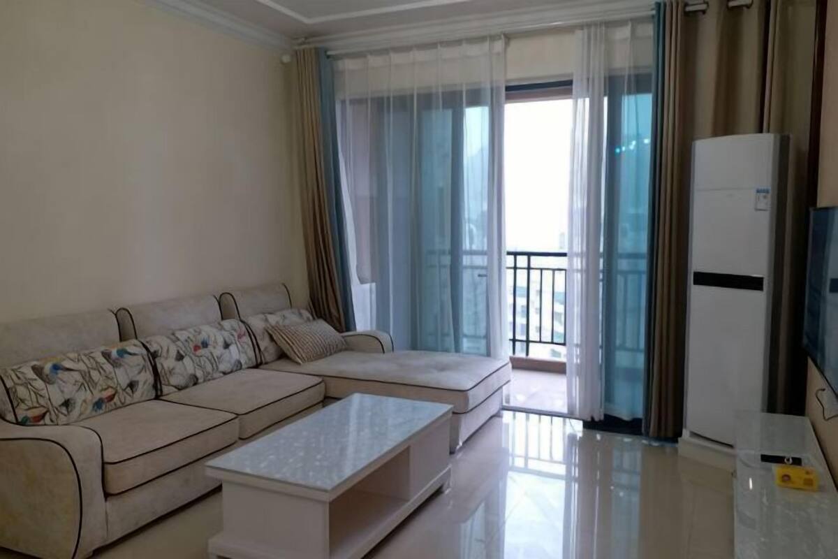 A living room with a sofa, a coffee table, a TV, and a refrigerator.