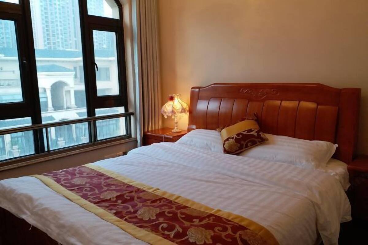 A neatly made bed with a patterned bedspread, a wooden headboard, and a bedside table with a lamp.