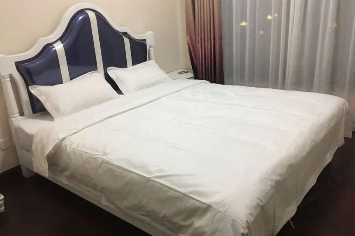 A neatly made bed with white bedding and a headboard with blue and white trim.