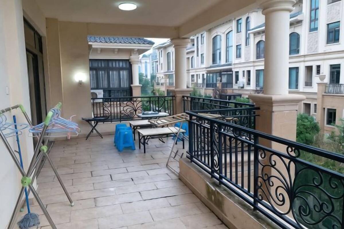 A balcony with a tiled floor, a metal railing, and a view of neighboring buildings.