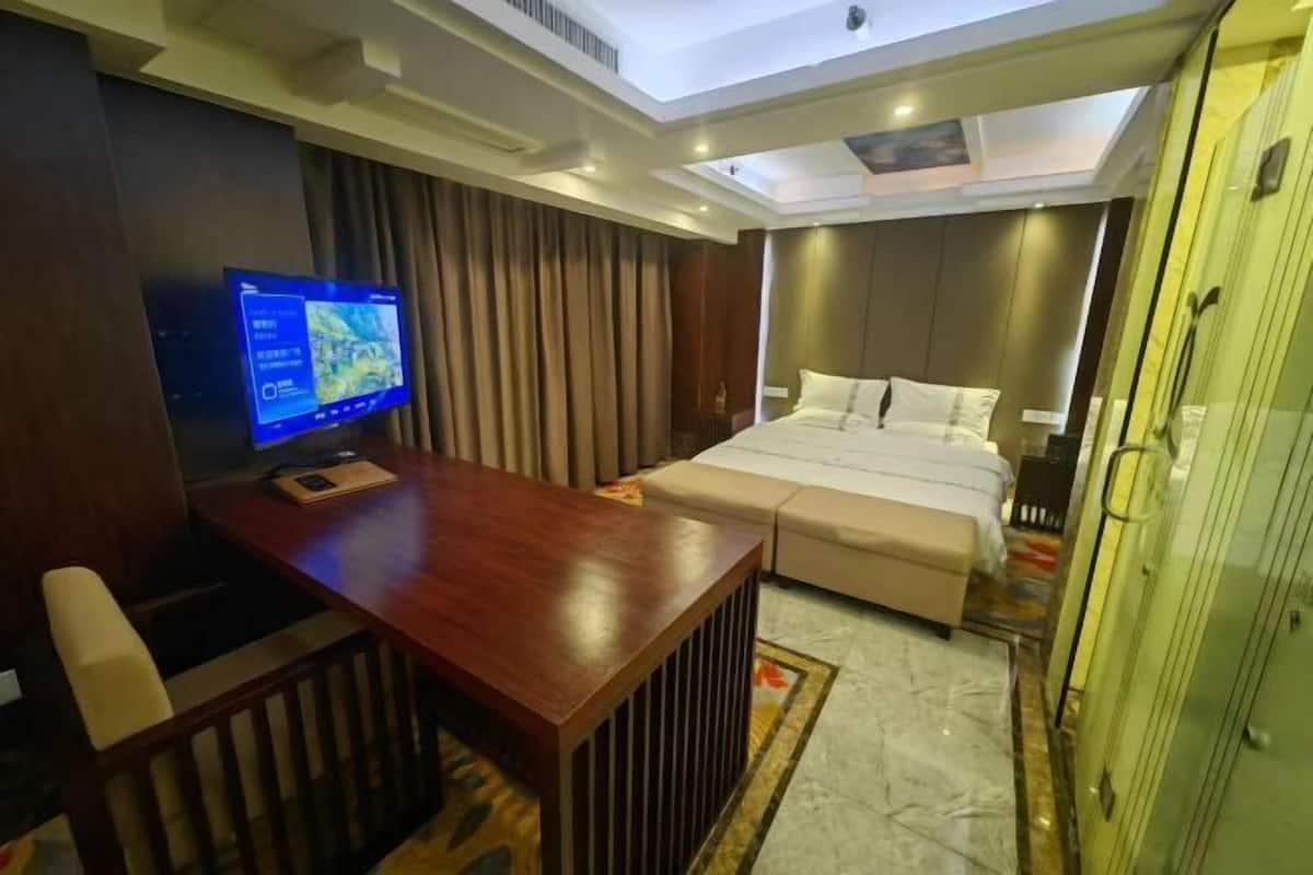 Une chambre d’hôtel comprenant un lit, un bureau, une télévision et une armoire.