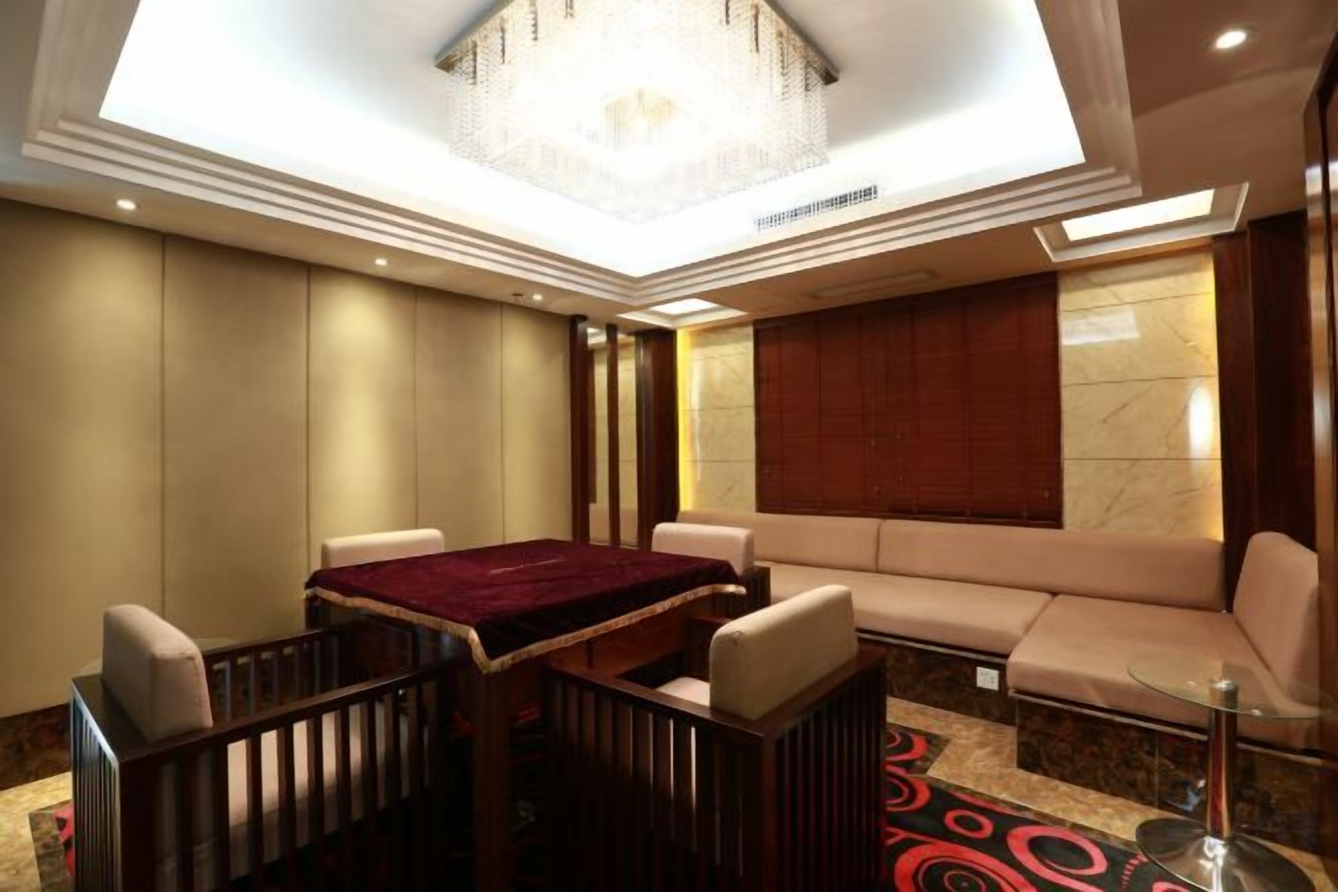 A hotel room with a dining table, sofa, and a chandelier.
