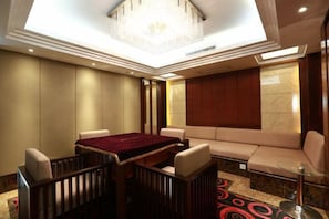 A hotel room with a dining table, sofa, and a chandelier. - Ding Chang Hotel (Xiangzhou)
