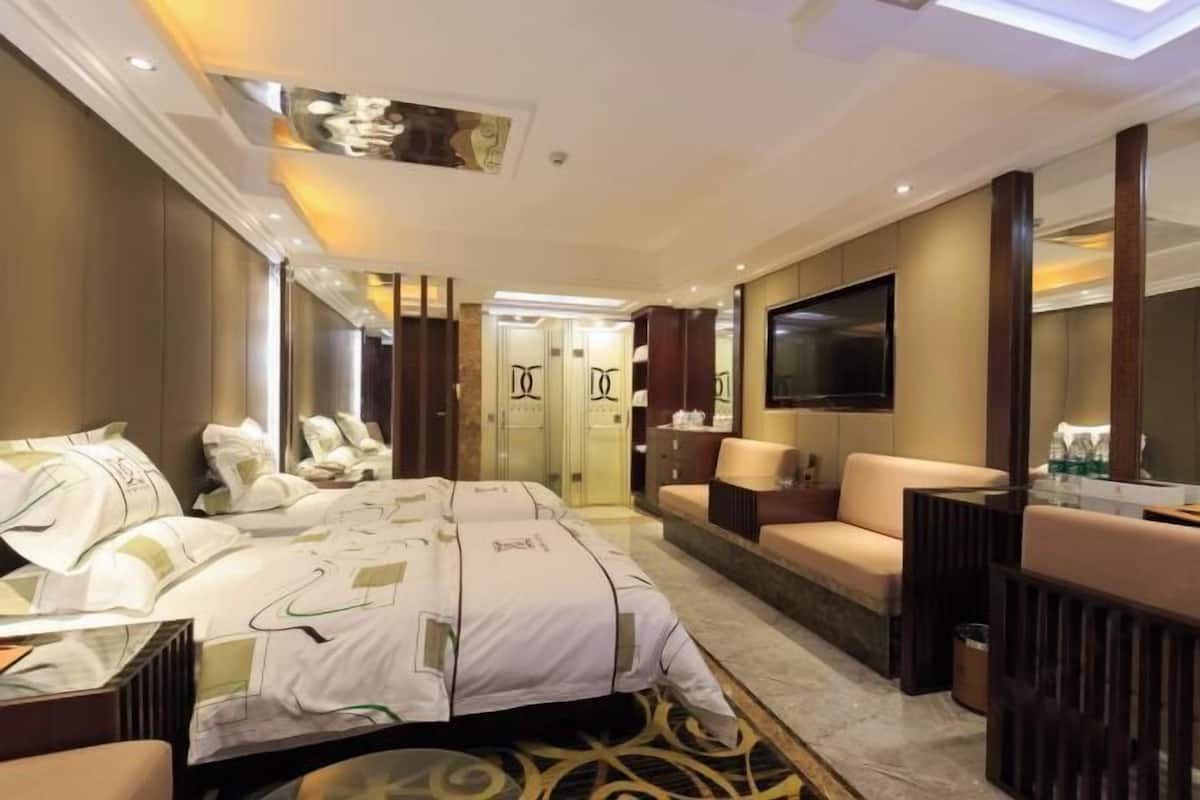 Une chambre d’hôtel avec un grand lit, un canapé, une télévision et un miroir.