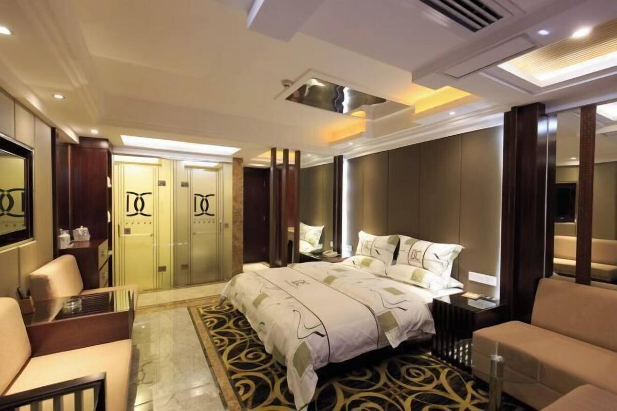 Une chambre d’hôtel dotée d’un grand lit, d’un coin salon, d’un bureau et d’une armoire.