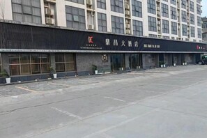 A building with a large entrance, multiple windows, and a parking lot.