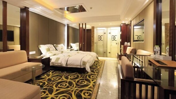 Una habitación de hotel con cama, sofá, escritorio y una pared divisoria de vidrio.