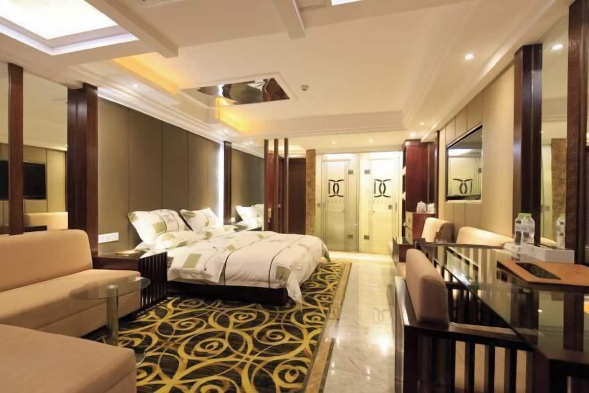 Une chambre d’hôtel comprenant un lit, un canapé, un bureau et une cloison en verre.