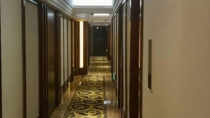 Un pasillo con alfombra estampada, puertas de madera y una lámpara en el techo.
