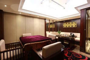 A hotel room with a dining table, chairs, a sofa, a coffee table, and a decorative mirror. - Ding Chang Hotel (Xiangzhou)