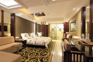 Habitación de hotel con una cama grande, un sofá, un escritorio y un espejo.