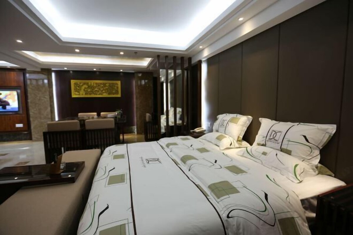 A modern hotel room with a large bed, a desk, and a seating area.