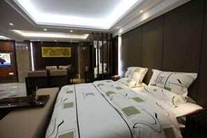 A modern hotel room with a large bed, a desk, and a seating area.