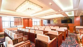 A conference room with rows of chairs, a stage with a podium, and a large screen.