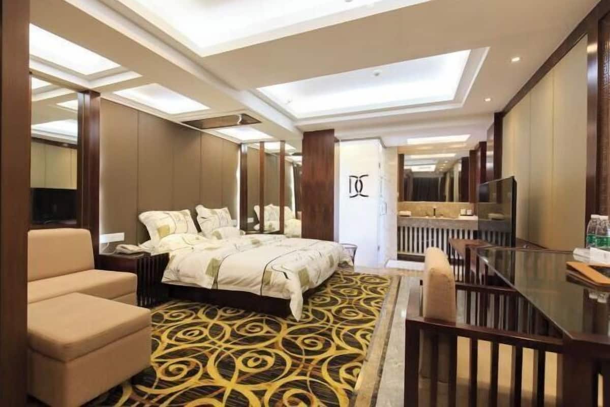 Une chambre d’hôtel avec un grand lit, un canapé, un bureau et un miroir.