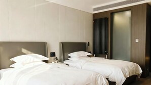 Habitación de hotel con dos camas, una mesita de noche y una puerta con diseño de persianas verticales.