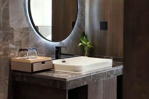 A modern bathroom with a rectangular sink, a round mirror, and a wooden vanity. - Rushan Hotel (Rushan)