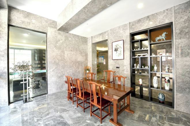 Un comedor con una mesa y sillas de madera, una puerta de cristal que da a la cocina, y una vitrina con adornos.