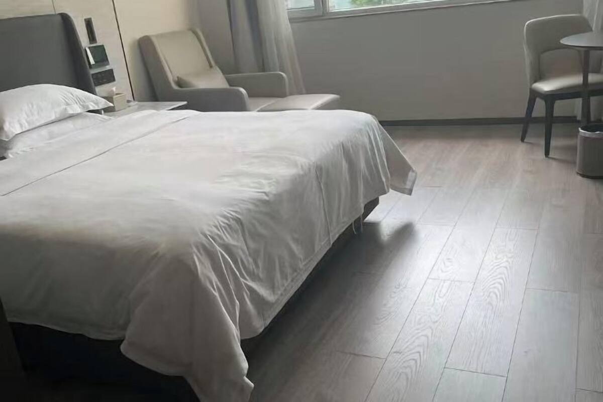 A hotel room with a large bed, a chair, a small table, and a window.