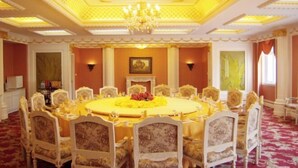 Un comedor formal con una mesa redonda, sillas ornamentadas y una araña.