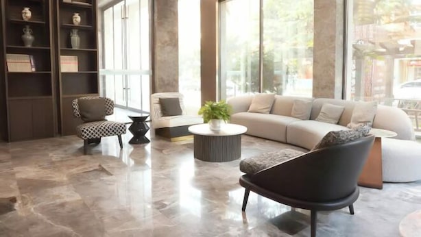 Una sala de estar moderna con un sofá, sillones, una mesa de centro y una estantería.