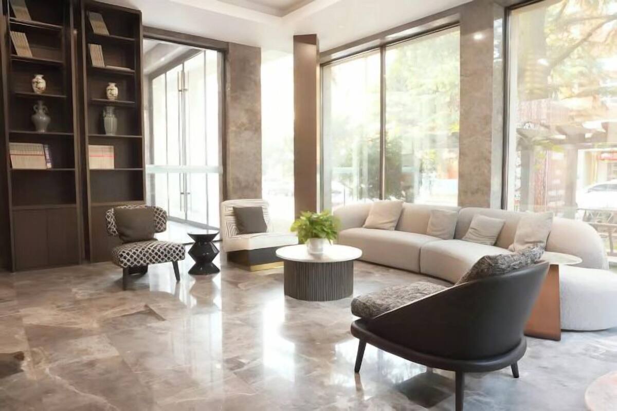 A modern living room with a sofa, armchairs, a coffee table, and a bookshelf.