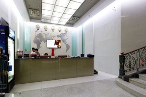 A reception area with a world map on the wall, a reception desk, and a staircase. - Meicheng Hotel (Guangzhou Zhujiang New Town Subway Station) (Guangzhou)