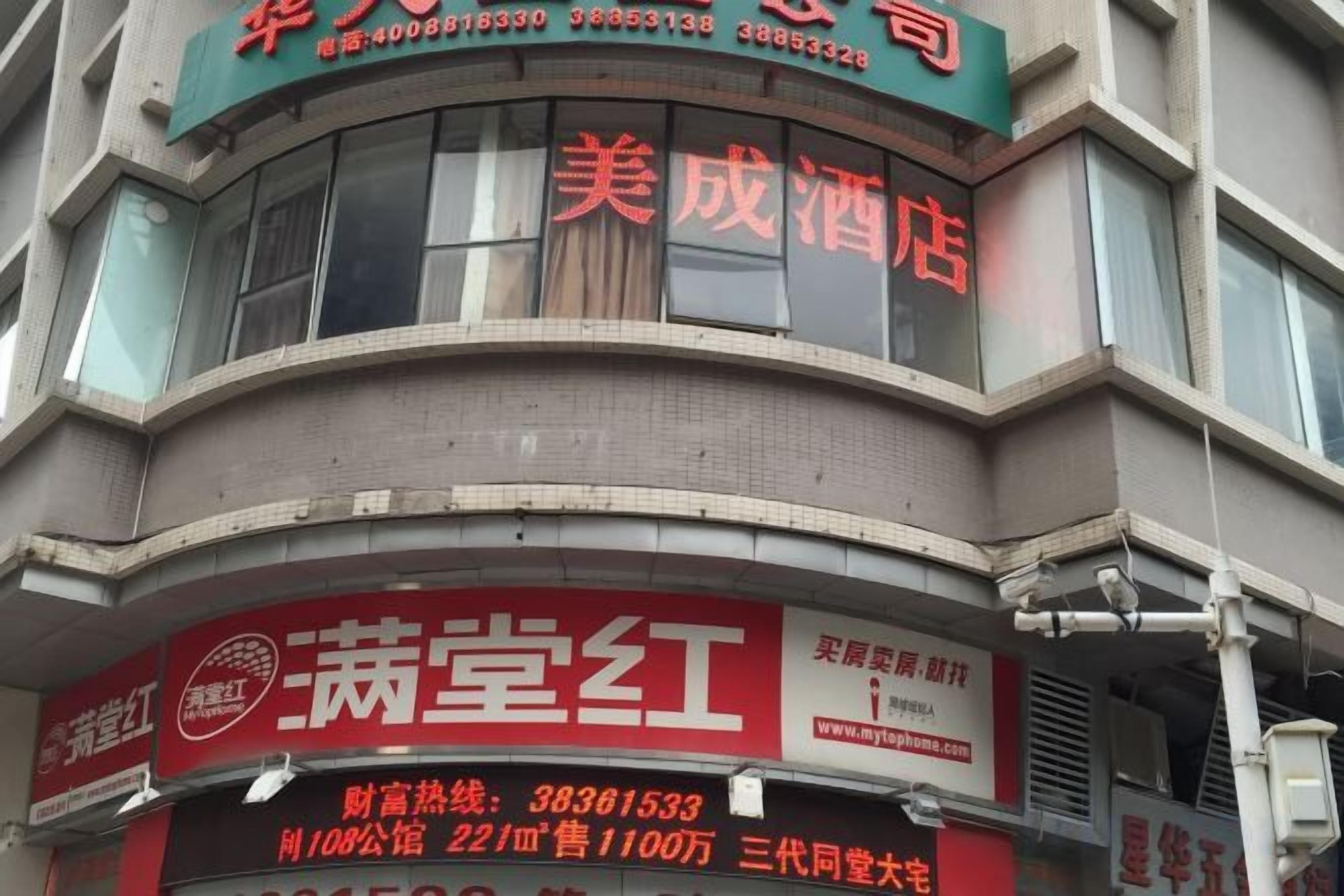 A building with multiple signs, including one for '美成酒店' and another for '菊堂红'.