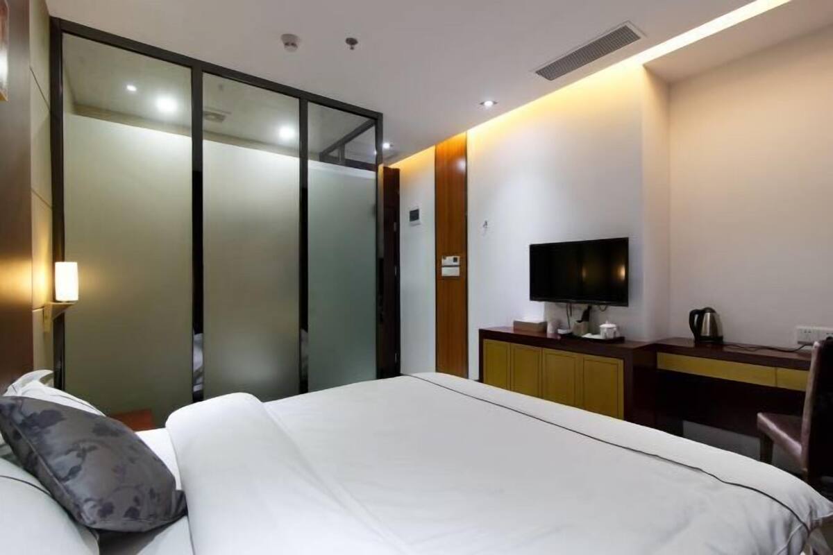 A hotel room with a bed, a desk, a television, and a wardrobe.