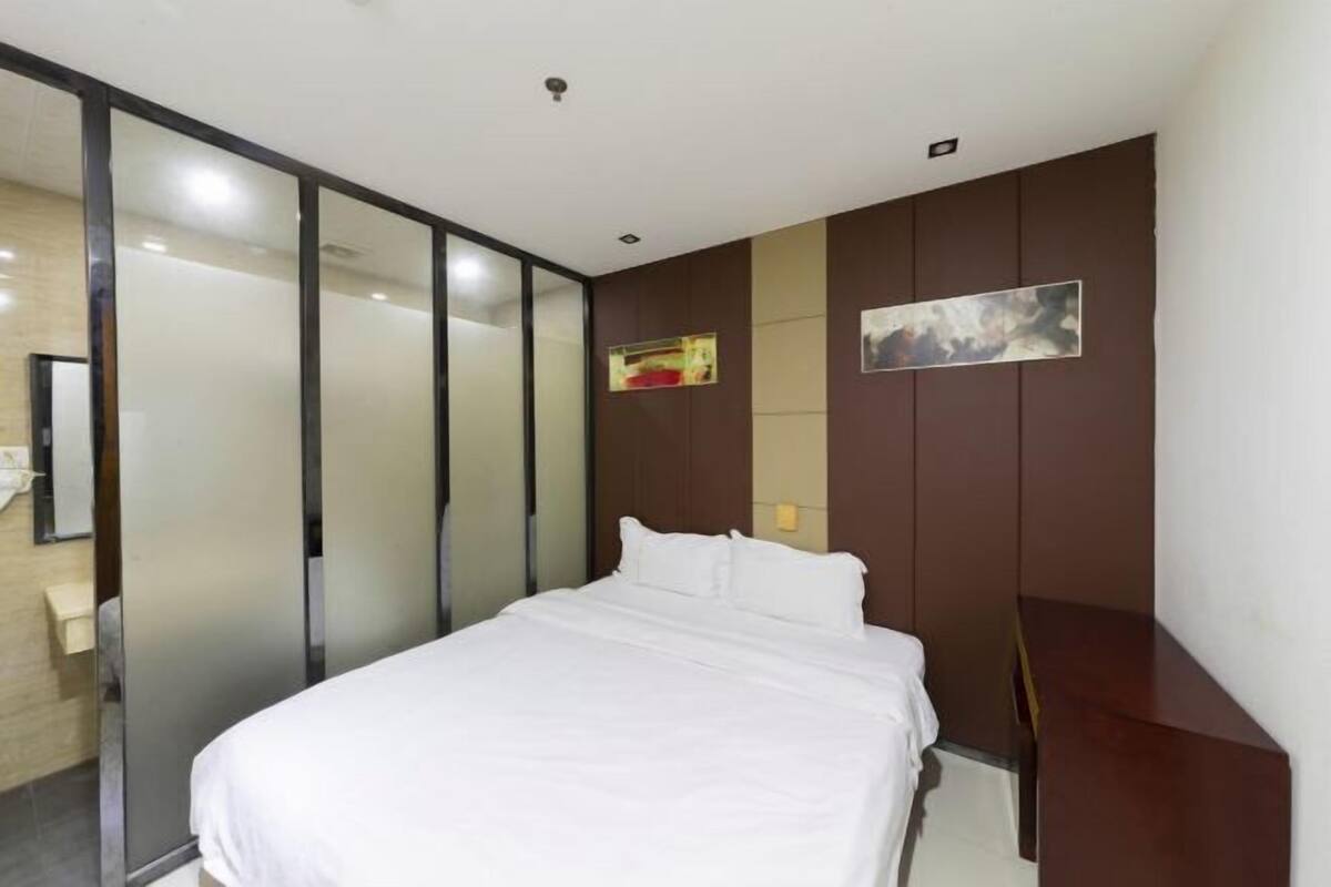 A modern hotel room with a bed, a sliding glass door, and a wall-mounted artwork.