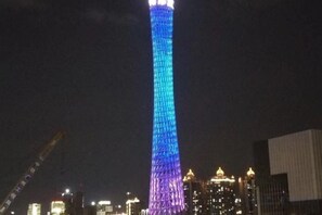A tall building with a vertical light pattern, surrounded by other buildings. - Meicheng Hotel (Guangzhou Zhujiang New Town Subway Station) (Guangzhou)