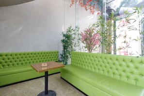 A green sofa and a small table in a room with a glass wall. - Meicheng Hotel (Guangzhou Zhujiang New Town Subway Station) (Guangzhou)