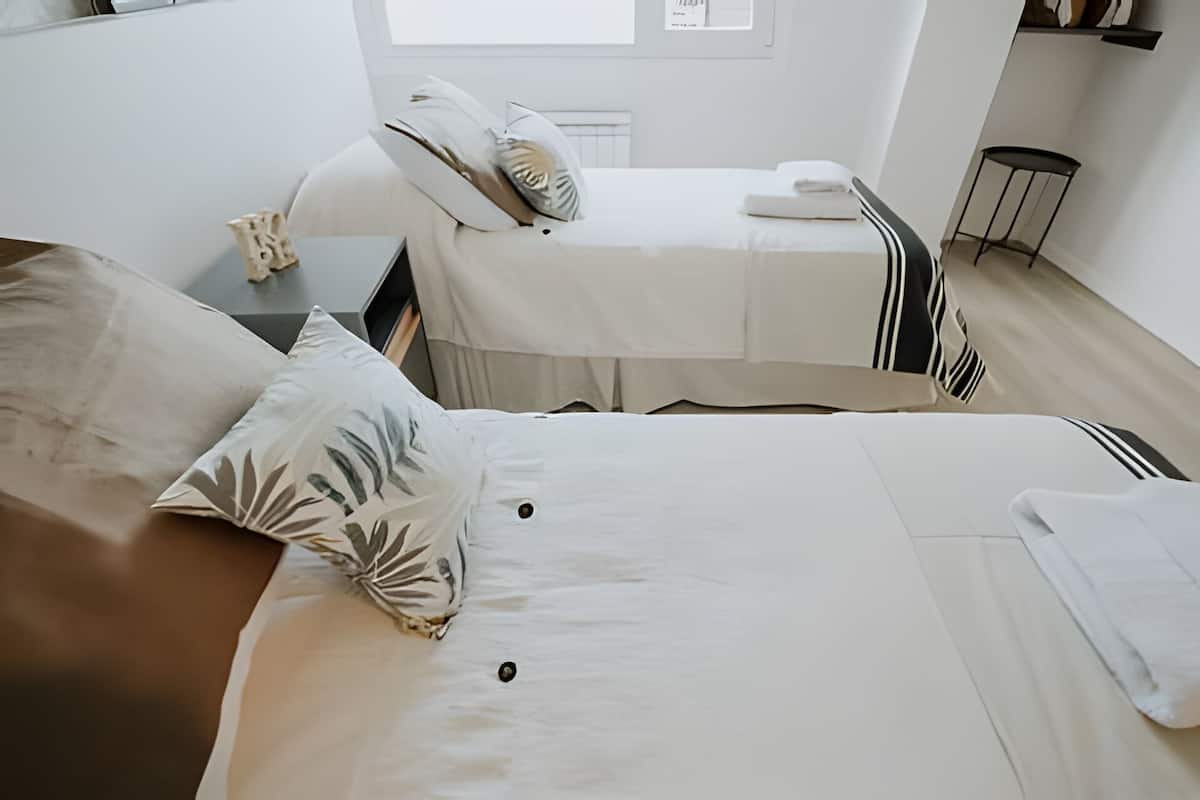 Une chambre d’hôtel au décor minimaliste, avec deux lits, une petite table et une chaise.