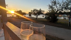 A balcony with two glasses of white wine, overlooking a lake with a sunset. - 8 min to Rocker B - Cozy Lakefront Escape at PK Lake  (Graford)
