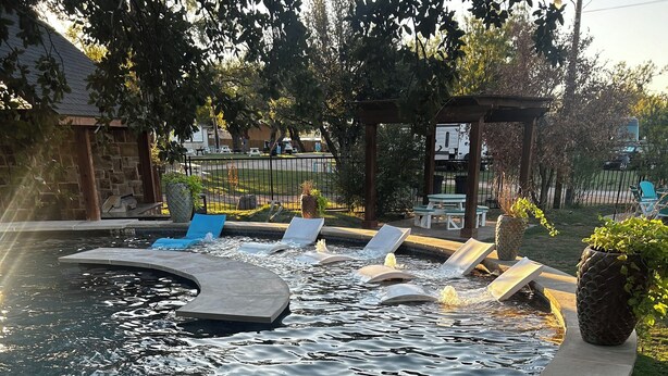A swimming pool with multiple water features and lounge chairs. - 8 min to Rocker B - Cozy Lakefront Escape at PK Lake  (Graford)