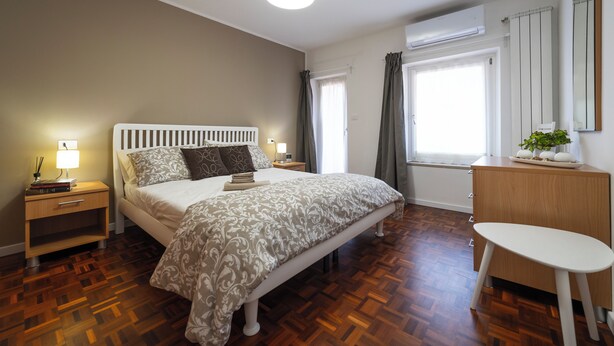 A bedroom with a bed, bedside tables, a dresser, and a chair. - Casa Marlò Centro Storico (Cividale del Friuli)