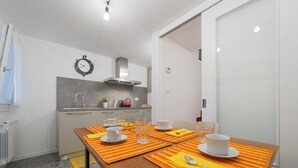 A modern kitchen with a dining table set for four, equipped with basic amenities. - Casa Marlò Centro Storico (Cividale del Friuli)