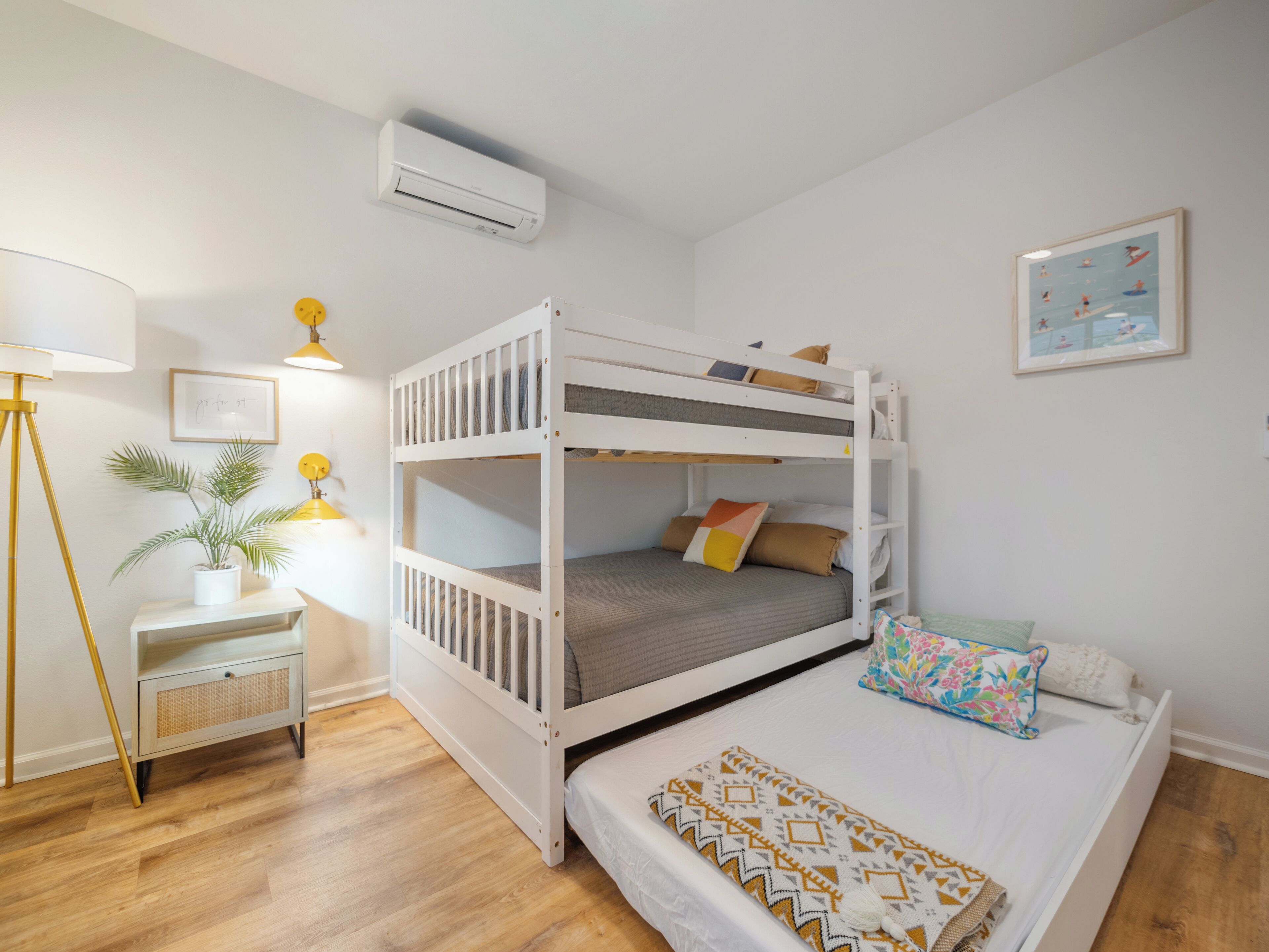 A bunk bed room with a desk, lamp, and air conditioning unit.