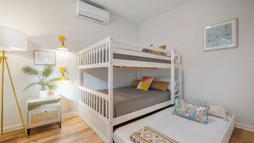 A bunk bed room with a desk, lamp, and air conditioning unit.