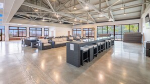 Un espacio interior amplio con techos altos, ventanas grandes y una larga barra con taburetes.