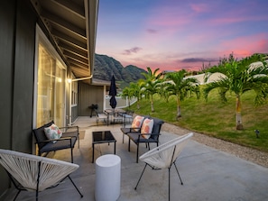 Une terrasse avec des meubles d’extérieur, une vue sur les montagnes et un coucher de soleil.