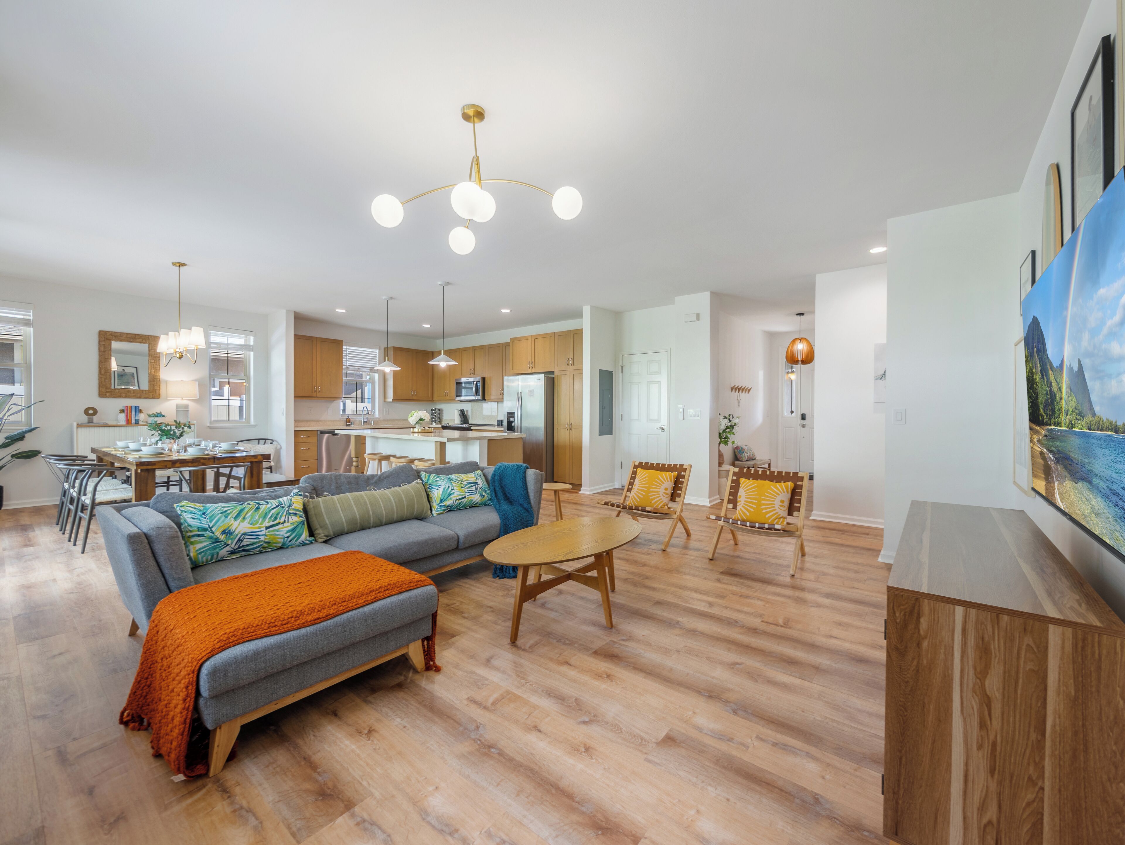 Amplia sala de estar con un sofá gris, una mesa de centro de madera y un comedor con mesa y sillas de madera.