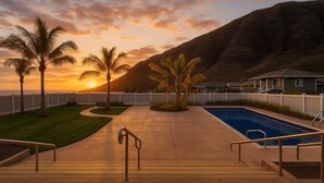 Una piscina con vistas a una puesta de sol y montañas.