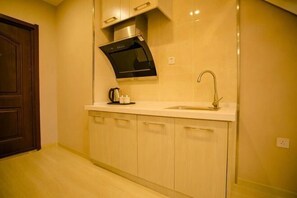 A kitchen with a microwave, sink, and cabinets. - Fuzhen Hotel Apartment (Changchun)