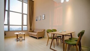 Une pièce comprenant un canapé, une table à manger, des chaises et une fenêtre avec des rideaux.