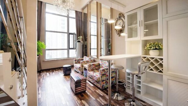 Un salon moderne avec un plancher en bois, un ensemble de canapés, une table basse, un tabouret de bar et une grande fenêtre avec des rideaux.
