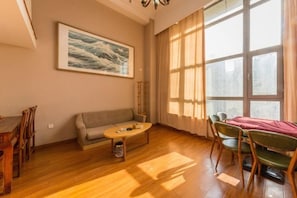 A living room with a sofa, a coffee table, and a dining area with chairs. - Fuzhen Hotel Apartment (Changchun)