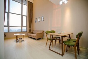 Una sala de estar amoblada con sofá, una mesa de comedor con sillas, una mesita redonda y una ventana con cortinas.